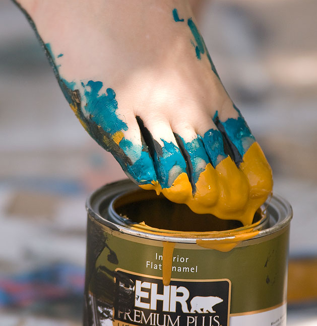 Trimble dips her toes into a bucket of paint to create an abstract painting in the Alla Prima style; she had her canvas spread on a sidewalk in a shady spot near the building where I teach.