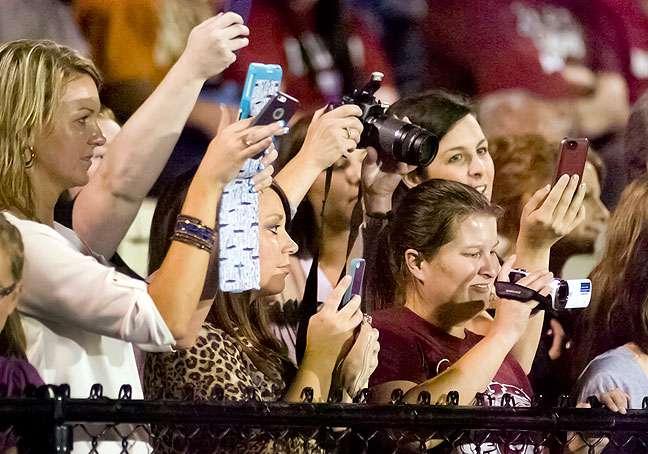 Parents and friends photograph cheerleader camp participants at a recent football game in Ada using camcorders, smart phones, tablets, and digital SLR cameras.