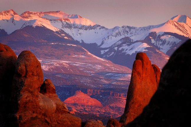The last rays of setting sun catch snow in the La Sal Mountains with the Windows Section of Arches National Park, Utah, in the foreground, in March 2004.