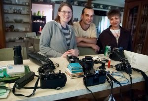 Jamie and her husband Ian, along with a friend of theirs, pose with some of their collected cameras, including the Pentax Auto 110, in 2012.