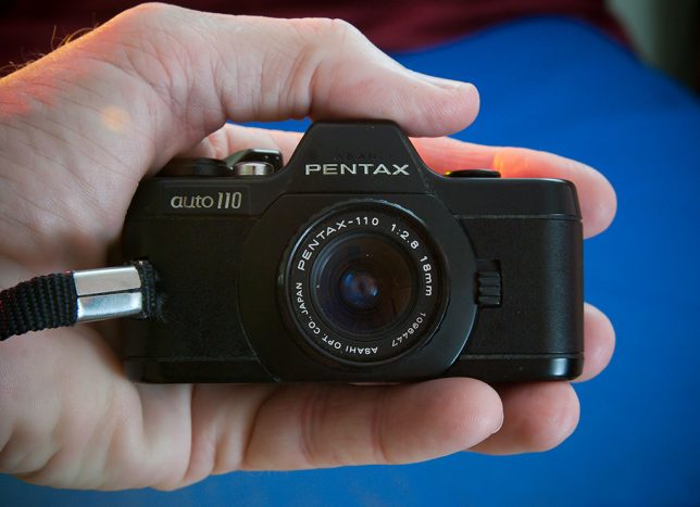 The Pentax Auto 110 sits in my hand, illustrating just how small this SLR camera really is.