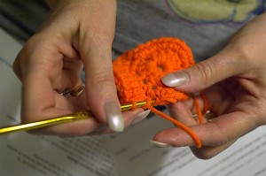 Abby works tonight to invent a stocking cap pattern out of her surplus blaze-orange yarn.