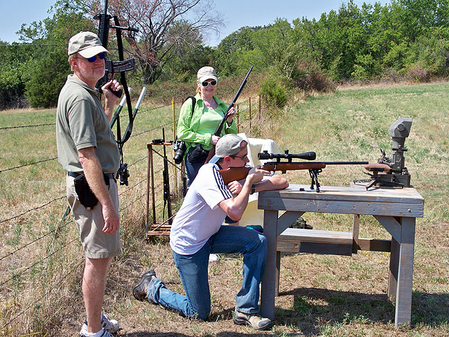 Holding my assault rifle, I watch as Abby and Matt take turns using Abby's father's shooting bench at the pond today.