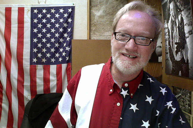 I am wearing one of my U. S. Flag shirts today. The flag behind me in my office is a permanent fixture. (Before anyone freaks out: those are reading glasses.)