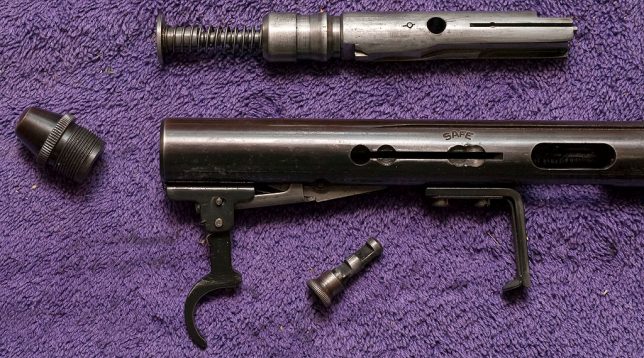 This is the bolt, receiver and trigger of the semi-auto rifle I cleaned last night. Removing the threaded cap on the left side of the frame is the first step in disassembling it.