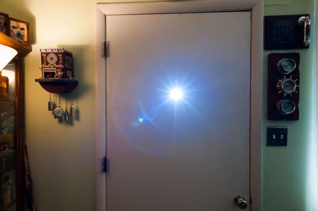 The lensing of the peephole causes the light to split into spectra. Moving the camera to different colored parts of the light changes the result.