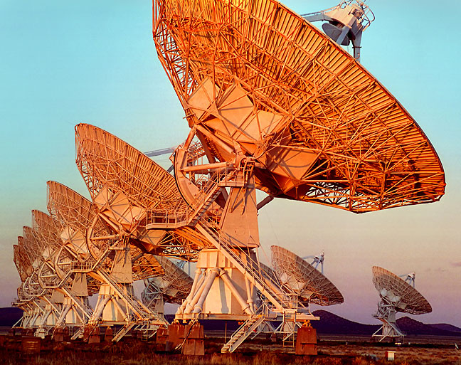 Radio telescope dishes of the Very Large Array near Magdalena, New Mexico, picks up golden light at sunset.