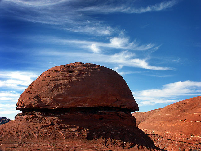 A mushroom-sharped rocks is set against a deep blue sky on the trail Canyonlands.