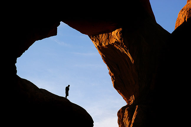 A hiker appears in an opening at Double Arch in The Windows section at Arches National Park.