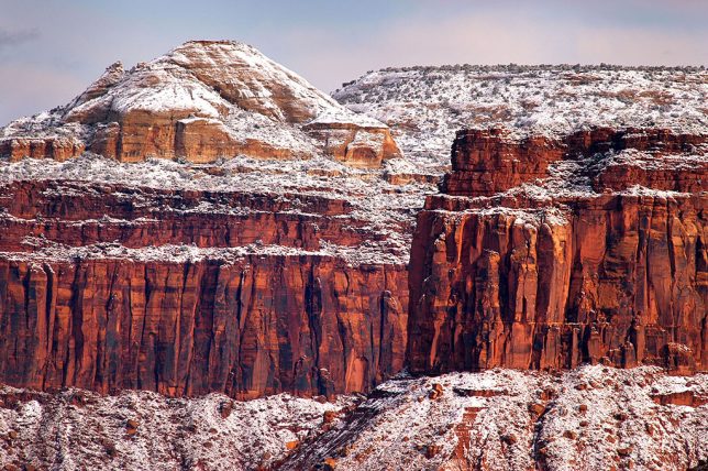 A light dusting of snow clings to Wingate Sandstone cliffs above Indian Creek.