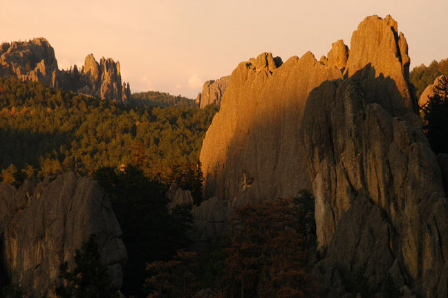 The shadows of sunset creep up on distant formations of the Needles Highway at Custer State Park.