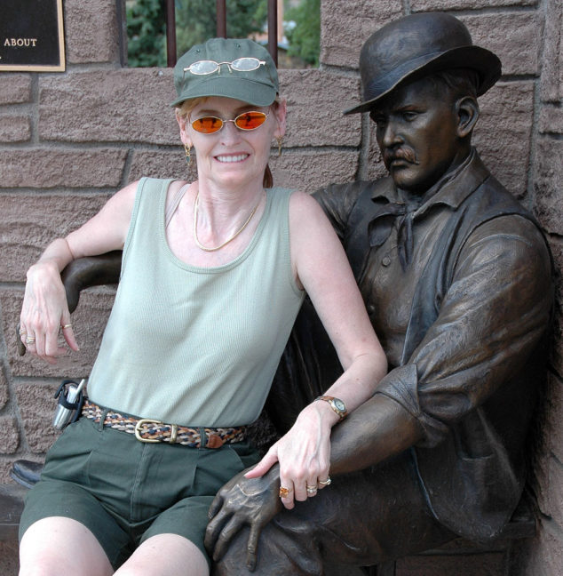Abby smiles as she poses with the bronze statue of The Sundance Kid in Sundance, Wyoming.