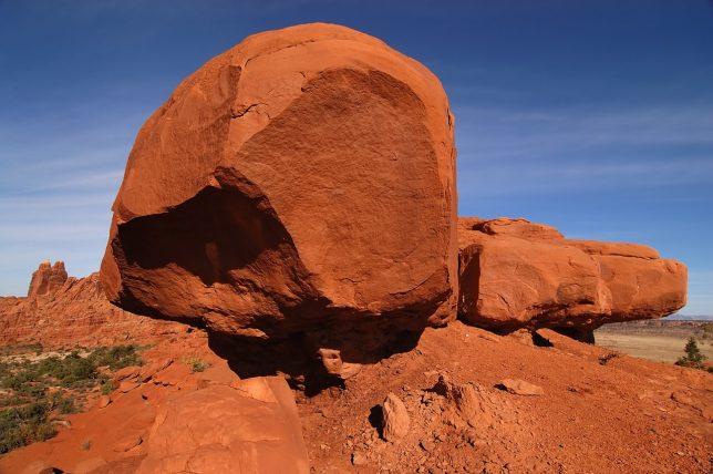 Giant deep-red sandstone boulders lead the way down the Klondike Bluffs trail at Arches.