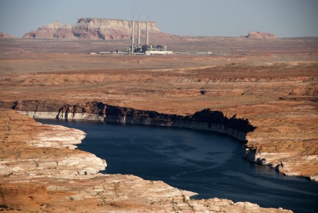 Looking east from Lone Rock, an arm of Lake Powell and the Navajo Generating Station are visible.