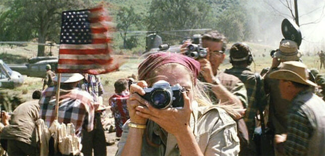 In this screenshot from the movie We Were Soldiers, a photographer makes pictures of a U.S. flag after the battle. 35mm news photography matured in the 1960s due in part to the demands of photographing the Vietnam War. 