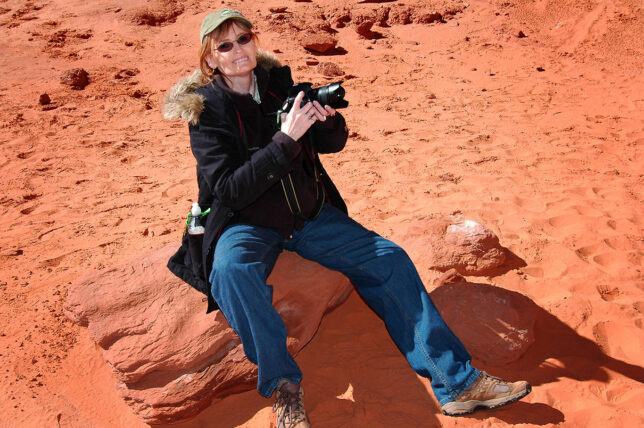 Abby sits on a stone as she photographs Monument Valley in October 2006.