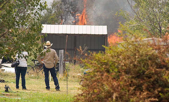 More than a dozen firefighting agencies were summonded to fight a fire in the Happyland area Saturday afternoon, August 20, 2011. Of note is the fact that the couple in this image is watching fire that is consuming "ladder fuels," brush and grass that surround structures.