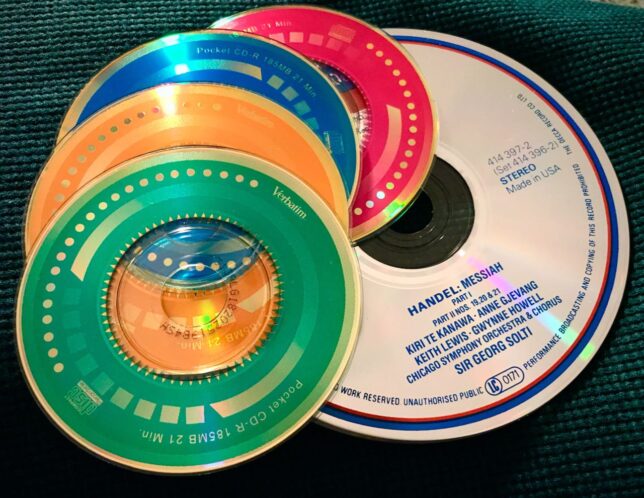 In this image, four "Pocket CD-R" discs sit on a normal-sized compact disc. I originally bought these for Abby because she drove a very small two-seat Toyota MR-2, and these discs fit perfectly in her center console. Buying blank media like discs, and later solid-state storage devices, felt very much like buying paper or film, for the same reason: I would be creating music-mix Pocket CDs!