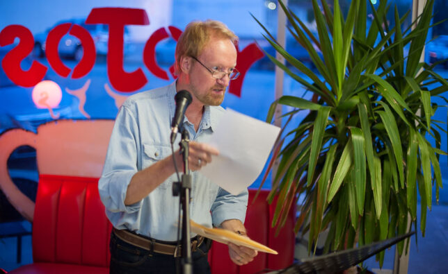 Richard reads material at "Open Mic Nyte" in 2018 in this photo by Mackenzee Ellen Crosby.