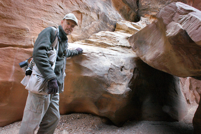 You host pauses for a self-portrait before squeezing under a boulder in Little Wild Horse Canyon.