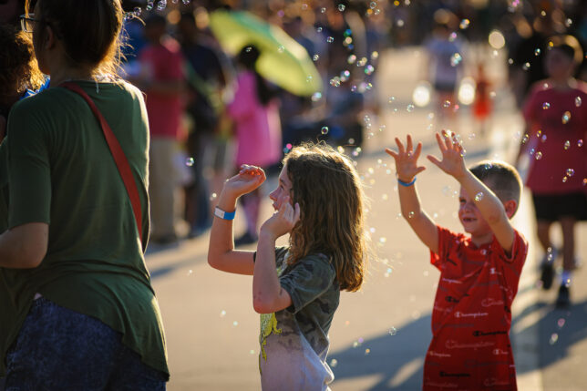 Kids play in bubbles as they wait in line for tethered balloon rides. 